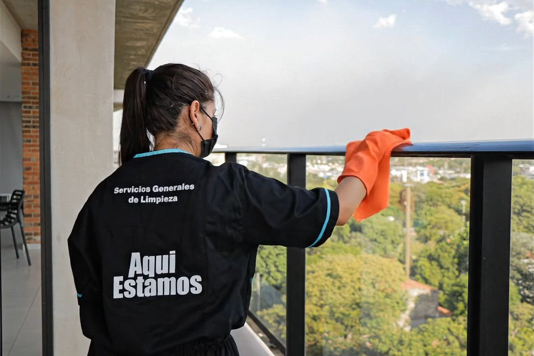 Personal uniformado de Aquí Estamos limpiando la baranda del balcón de una torre corporativa